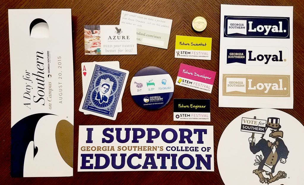 Door hanger, bumper sticker, playing cards, fans, stickers and business cards on a table